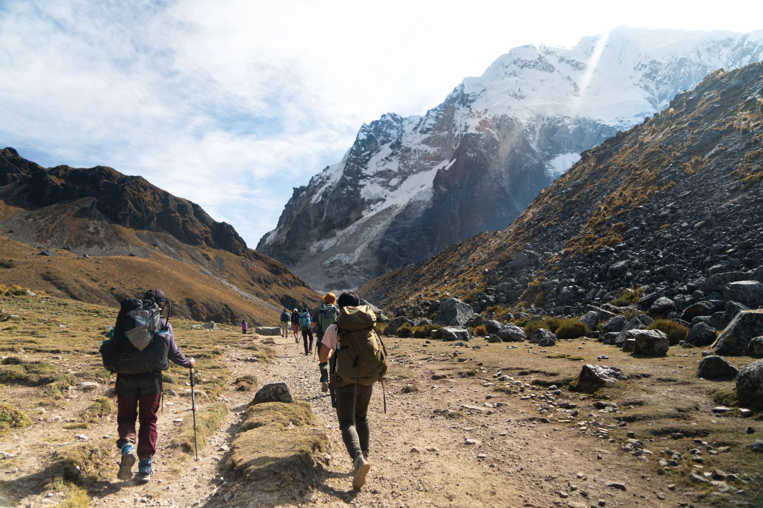 Peru, salkantay pass. Hikers walking along a trail in a mountainous area with snowy peaks in the background.