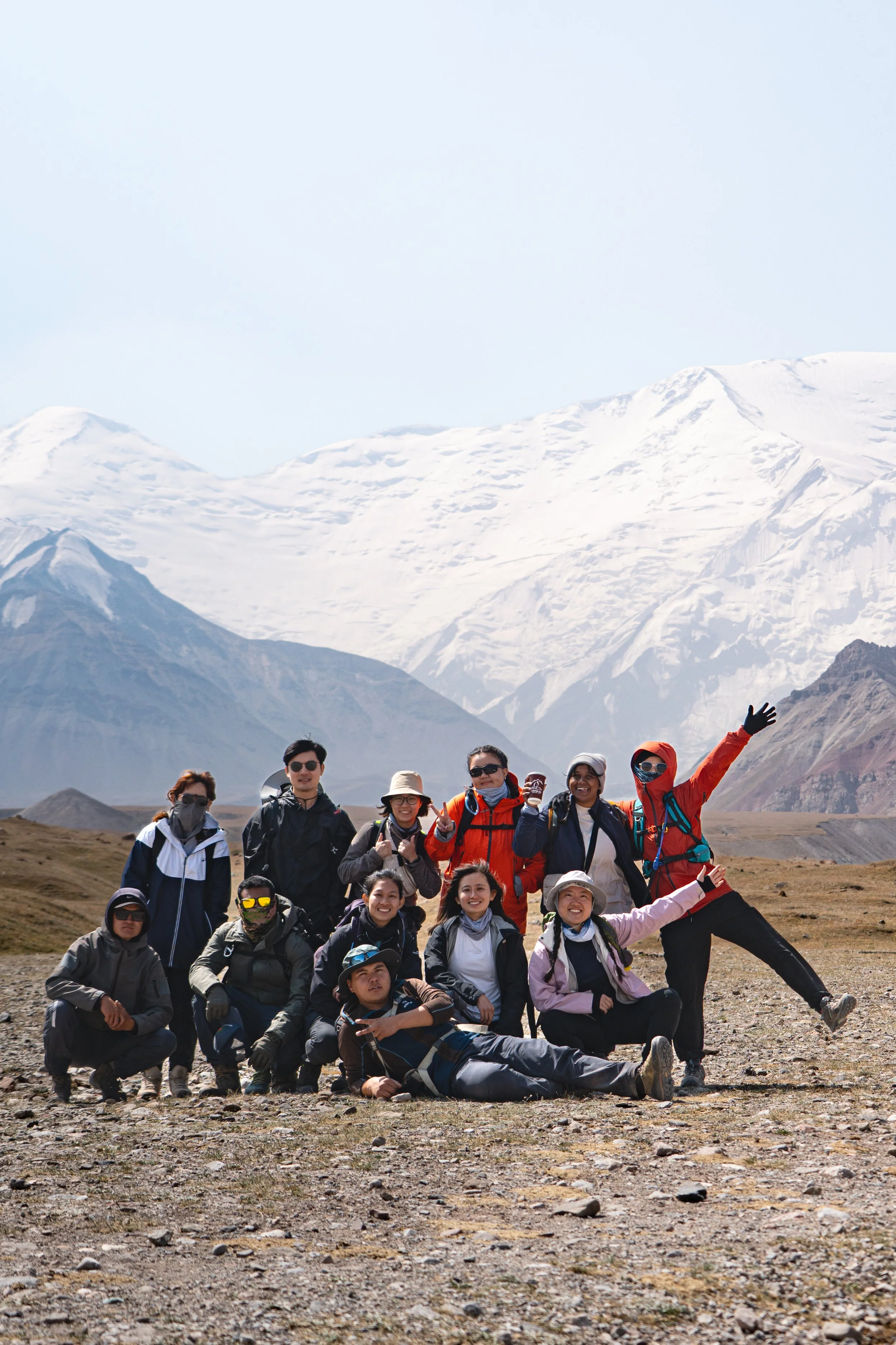 Group of hikers posing outdoors with snow-capped mountains in the background.