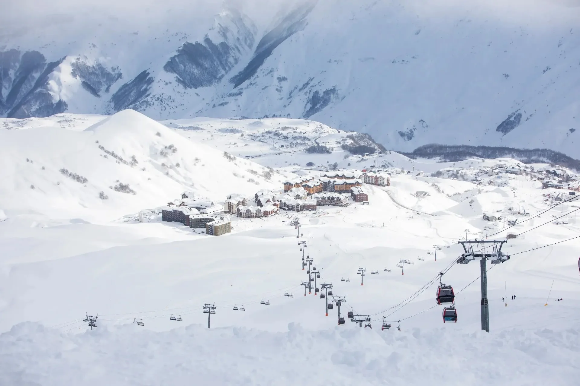 Georgia, Guduari Snow-covered mountain landscape with ski resort buildings in the background and ski lifts carrying skiers up the slopes.