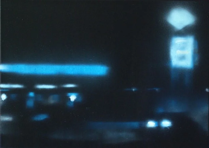 Nachtaufnahme einer dunklen Stadtstraße mit blauen Lichtern und einem leuchtenden Schild im Hintergrund.