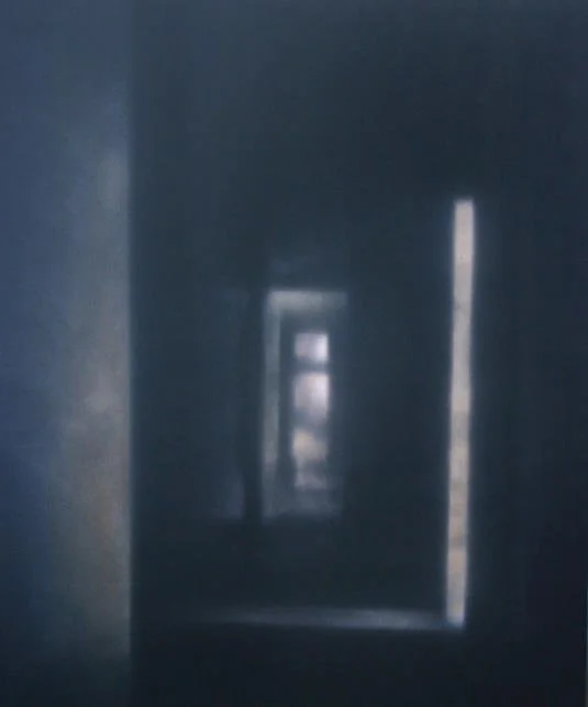 Blick durch eine dunkle Türöffnung auf eine Reihe weiterer Türen in einem Flur