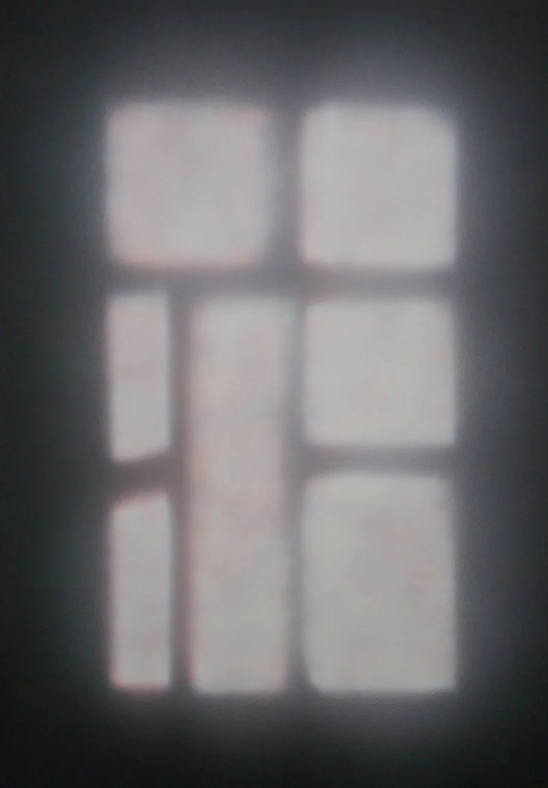 Schatten eines Fensters mit mehreren rechteckigen Paneelen an einer Wand