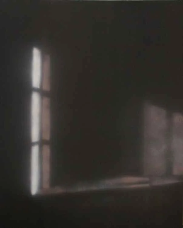 Dunkler Raum mit zwei schmalen, vertikalen Fensterflächen, durch die wenig Licht einfällt.