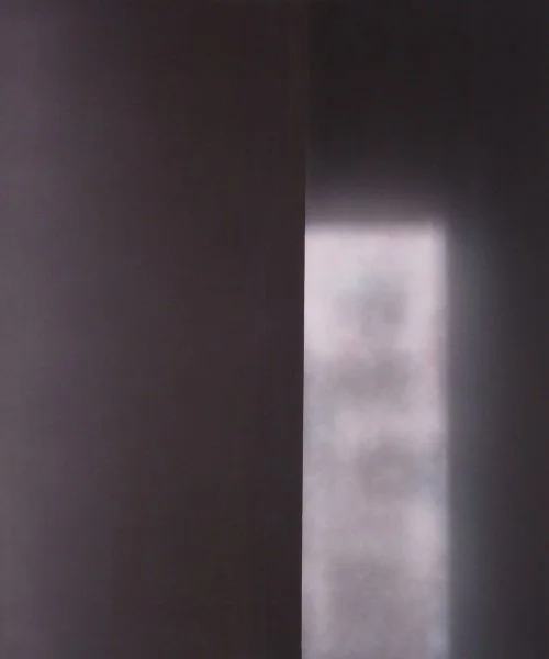 Ein schmaler dunkler Flur mit einer weißen beleuchteten Tür am Ende.