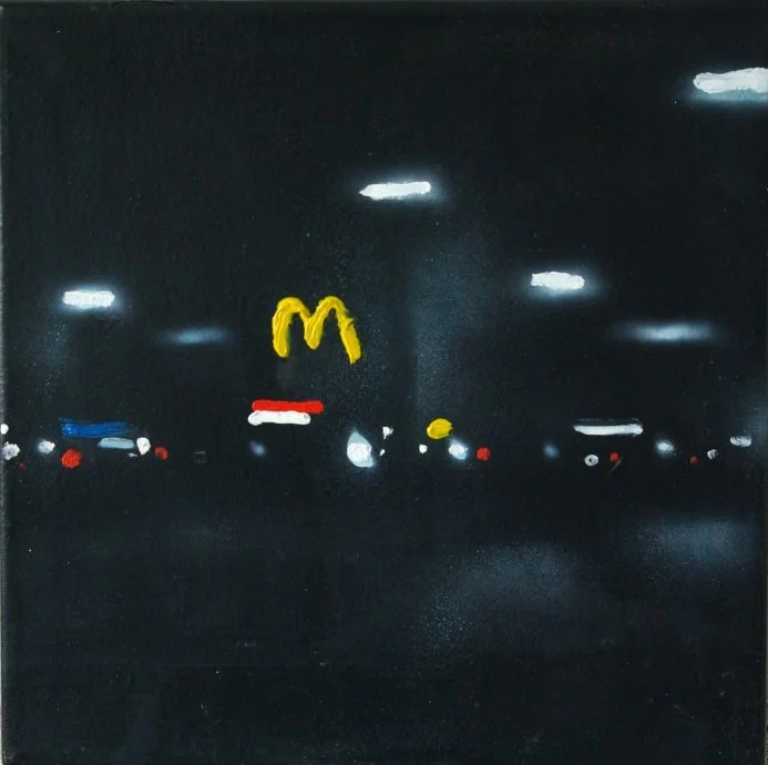 Nachtaufnahme einer Supermarkt-Parkplatz mit leuchtender McDonald's-Logoreklame im Hintergrund.