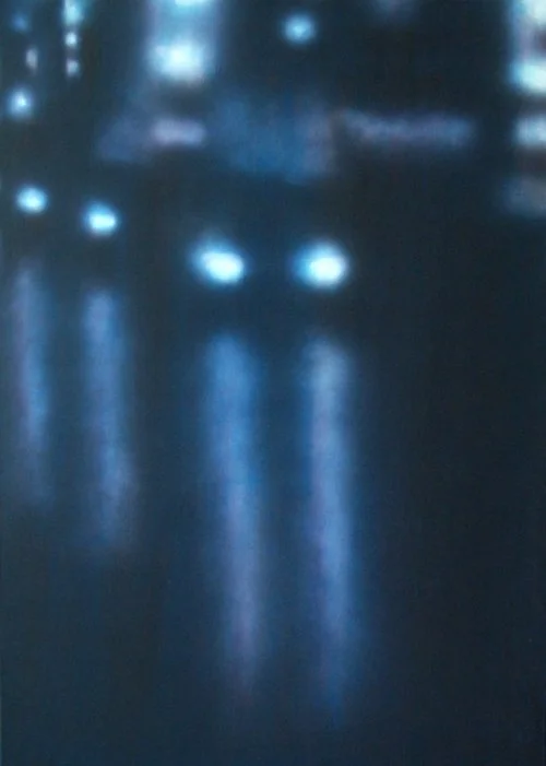 Unklare Aufnahme von Autos mit eingeschaltetem Licht auf nasser Straße bei Nacht.