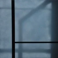 Nahaufnahme von einem Fenster mit schwarzen Rahmen und Sicht auf eine blaue Wand im Hintergrund.