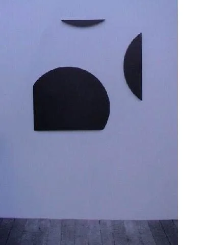 Abstrakte Wandkunst mit schwarzen geometrischen Formen auf weißem Hintergrund.