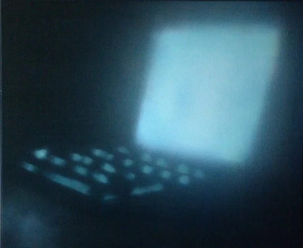 Ein dunkler Raum mit einem leuchtenden Computerbildschirm und Tastatur.