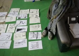 Blattkarten mit verschiedenen Zeichnungen und Skizzen, die auf dem grünen Boden liegen.