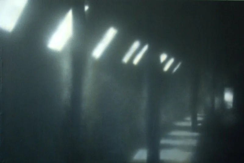 Ein dunkler, lange Flur mit Lichtstrahlen, die durch Oberlichter scheinen.