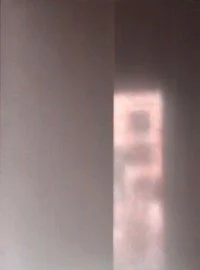 Eine Wand mit einem hellen Lichtstreifen, durch den man eine verschwommene Fensteröffnung sehen kann.