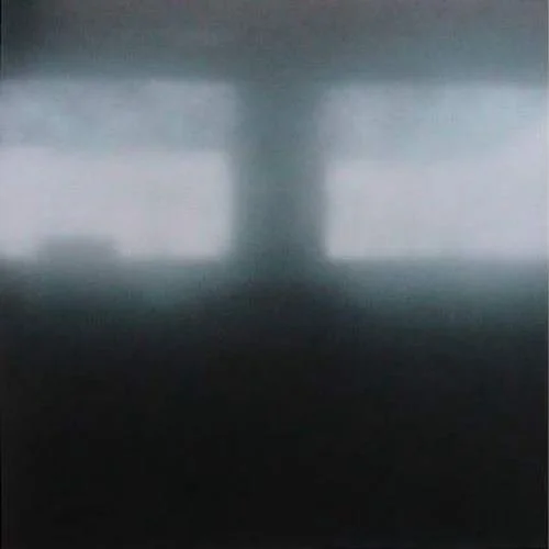 Ein dunkler, unscharfer Raum mit einer schmalen Lichtquelle in der Mitte, wahrscheinlich durch ein Fenster.