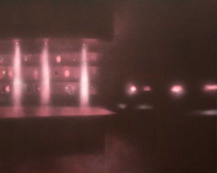 Mehrere vertikale Wasserstrahlen, die auf eine Wasserfläche treffen, und im Hintergrund Lichter in einem dunklen Raum.