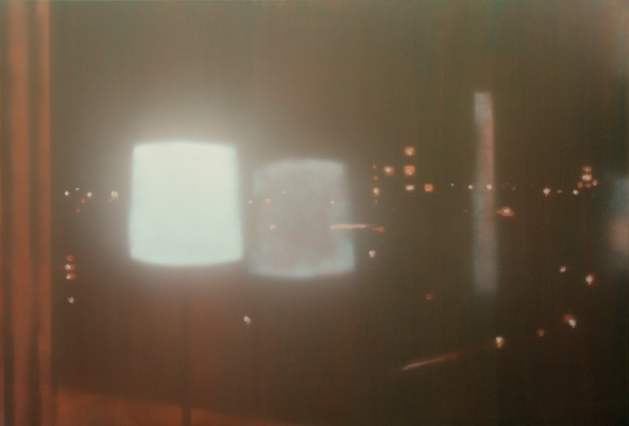 Ein Blick durch ein Fenster bei Nacht, mit reflektierenden Lichtern im Inneren.