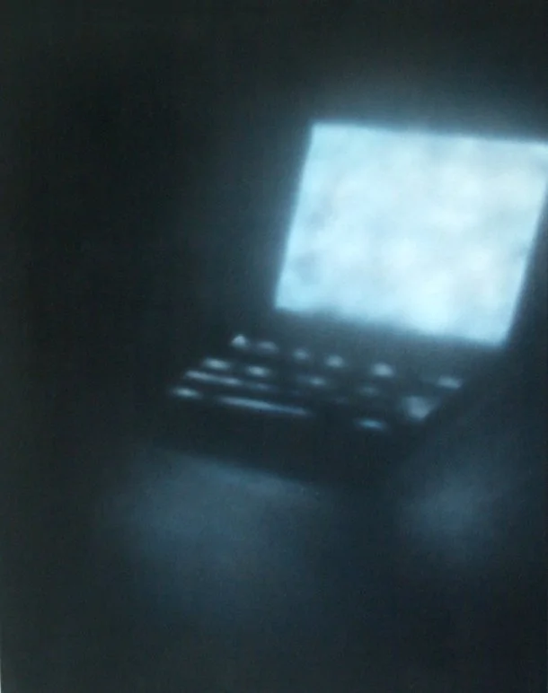 Ein leuchtender Laptop in dunklem Raum, Bildschirm zeigt helles Bild.