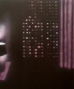 Ein dunkler Raum mit einem leuchtenden, pixelierten digitalen Display, das die Wörter 'MINUS INE'.