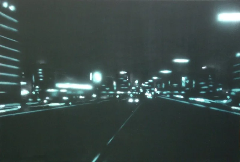 Bild einer nächtlichen Stadtstraße mit leuchtenden Gebäuden und Straßenbeleuchtung.