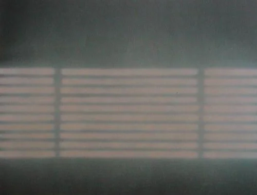 Ein Blick durch eine Fensterjalousie mit horizontalen Latten, Licht fällt durch die Schlitze.