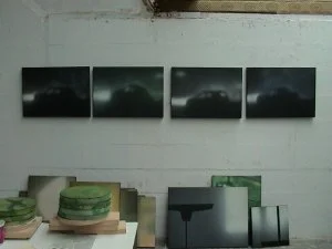 Vier dunkle, stürmische Himmelbilder in Serie an einer weißen Wand.