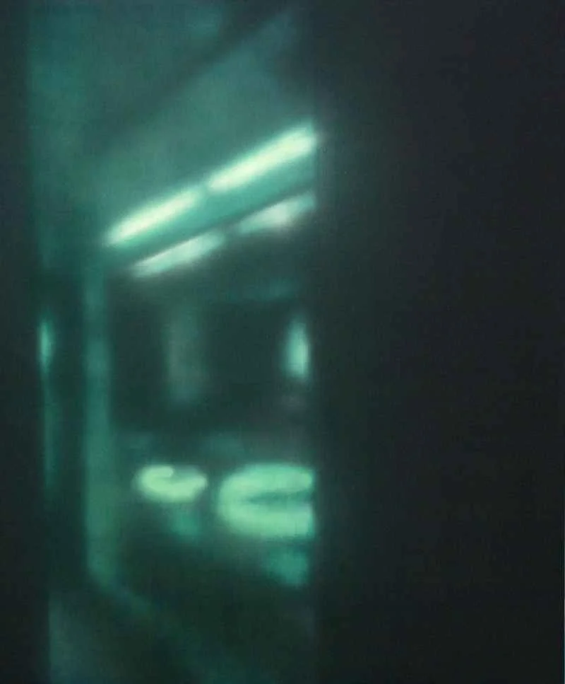 Dunkler Flur mit grünen und weißen Lichtreflexen auf den Wänden und dem Boden.