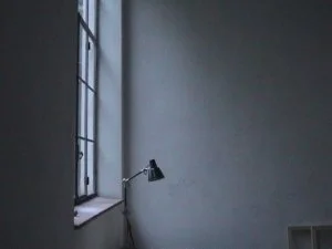 Leere weiße Wand neben ein Fenster mit einem schwarzen Schreibtischlampe an einem Schreibtisch