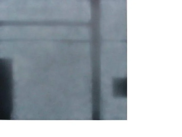 Ein verschwommenes, graues Bild, das eine Wand und einen vertikalen Balken zeigt.
