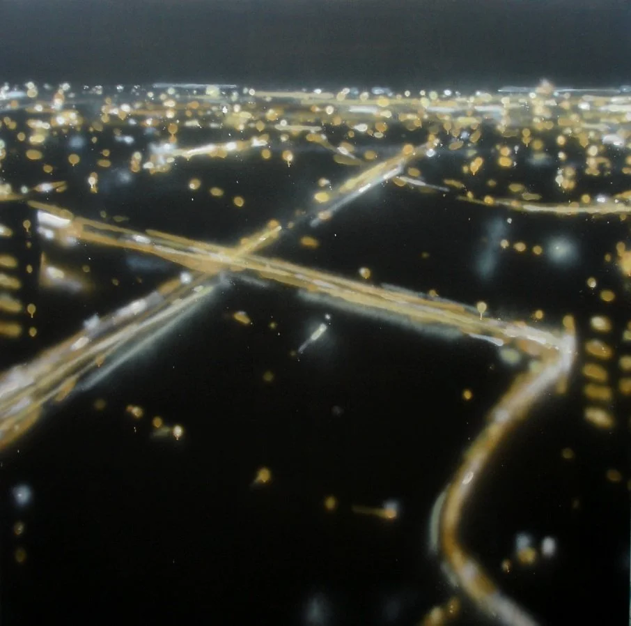 Luftaufnahme einer Stadt bei Nacht mit leuchtenden Straßen und Gebäuden.