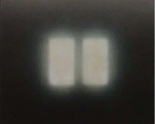 Ein Fenster mit durchscheinendem Licht, das durch eine dunkle Wand sichtbar ist.