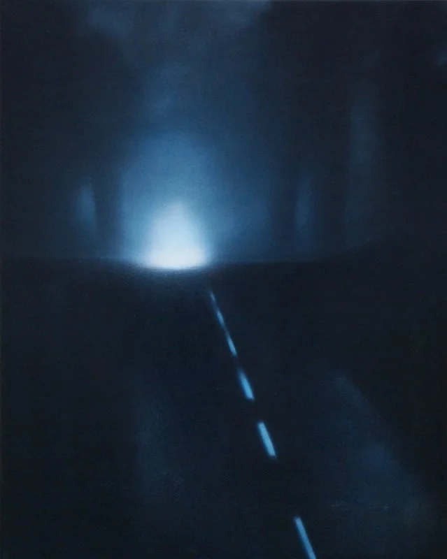 Straße bei Nacht mit einem hellen Licht am Horizont und einer durchgezogenen Linie in der Mitte.