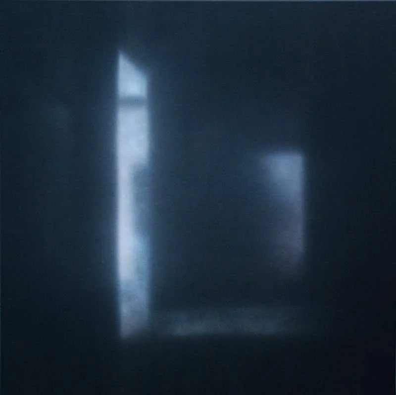 Schwarz-weißes Foto einer dunklen Wand mit Lichtstrahlen, die durch einen schmalen Spalt in einer Tür oder Fenster fallen.