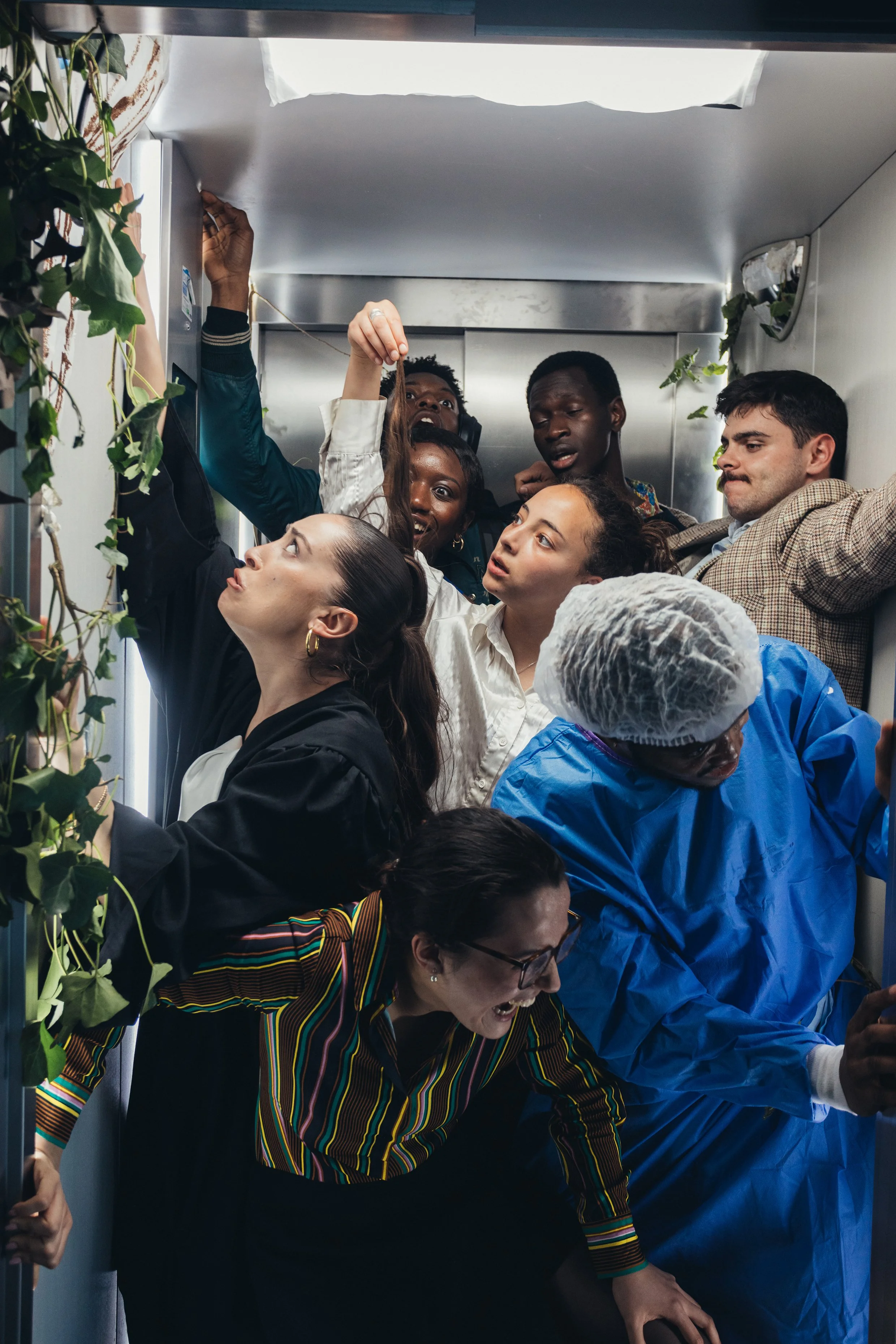 Un groupe diversifié de personnes dans un ascenseur, avec des plantes en décor.