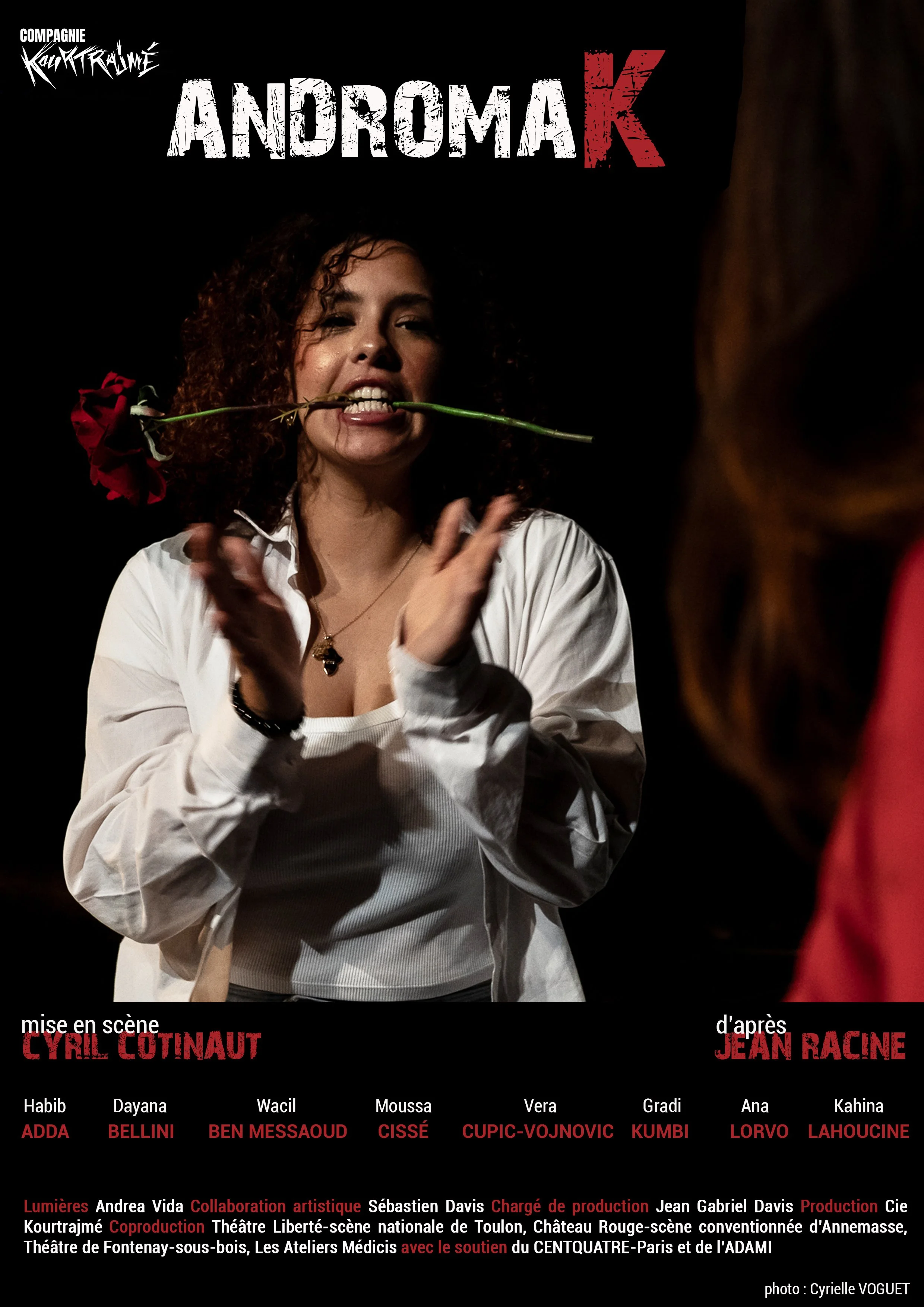 Une affiche de spectacle intitulée 'Andromak', montrant une femme avec des cheveux bouclés noir tirant une rose de sa bouche, portant une chemise blanche. Le nom de la metteure en scène est Cyril Cotinaut et le spectacle est d'après Jean Racine. La l