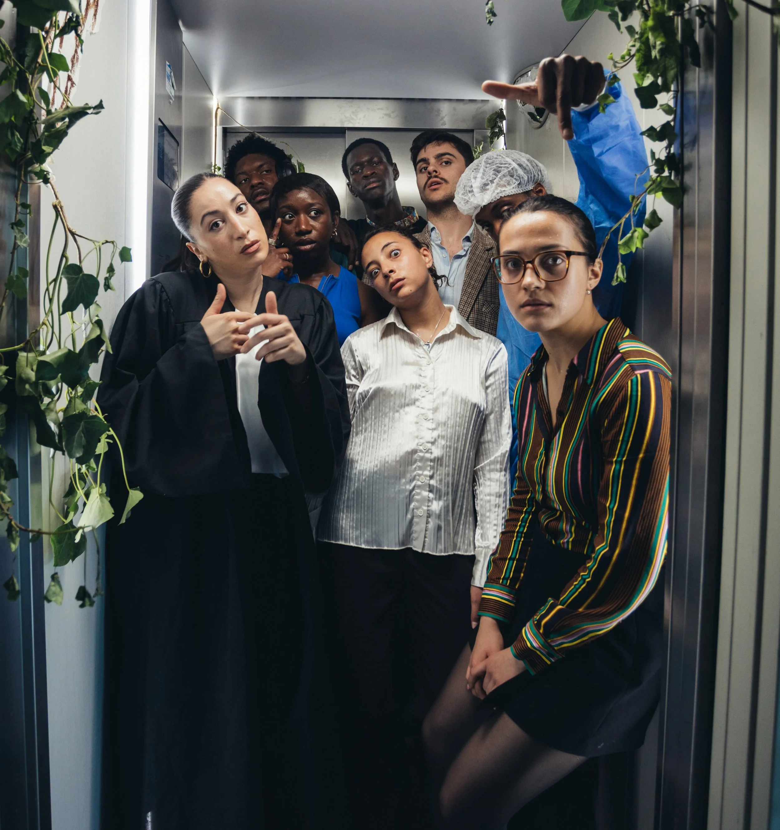 Groupe de personnes rassemblées dans un ascenseur avec des expressions curieuses ou étonnées.