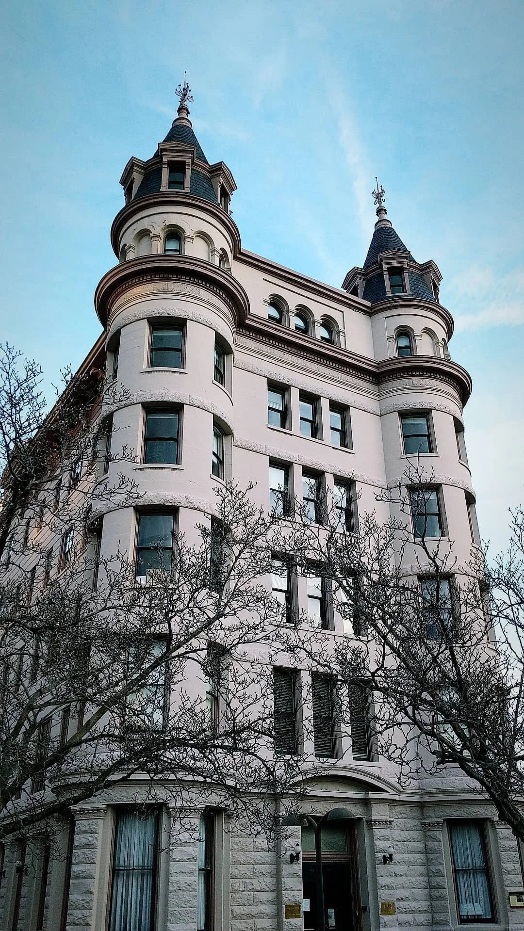 A tall, historic-style white building with rounded turrets and pointed rooftops against a blue sky.