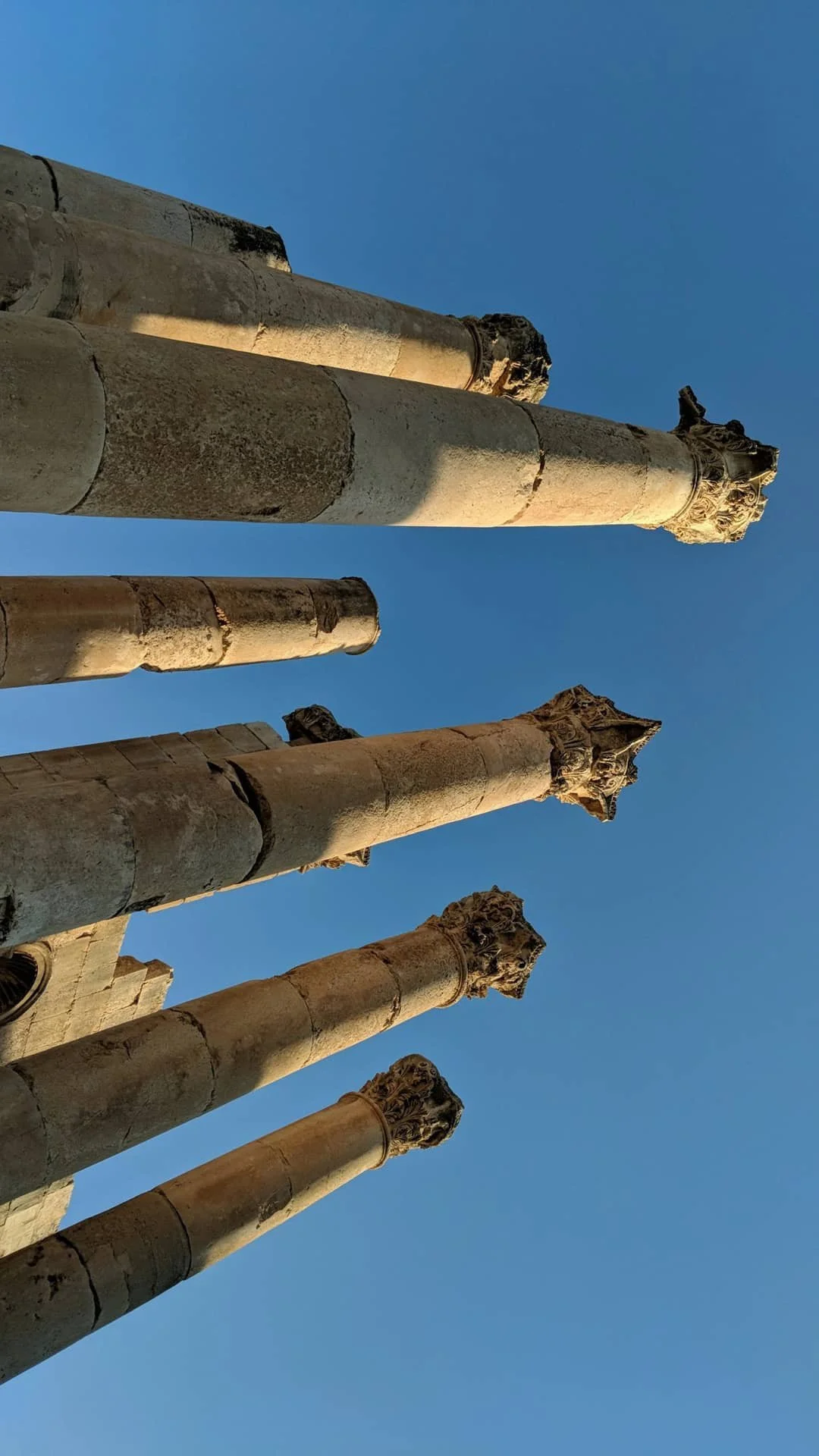 Ancient stone columns with ornate capitals against a clear blue sky.