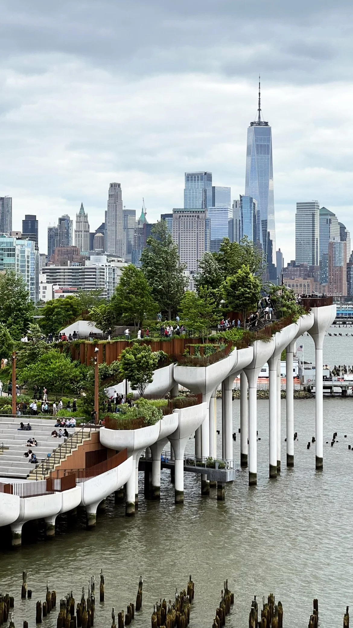 City skyline with prominent skyscraper and waterfront park with terraces and trees.