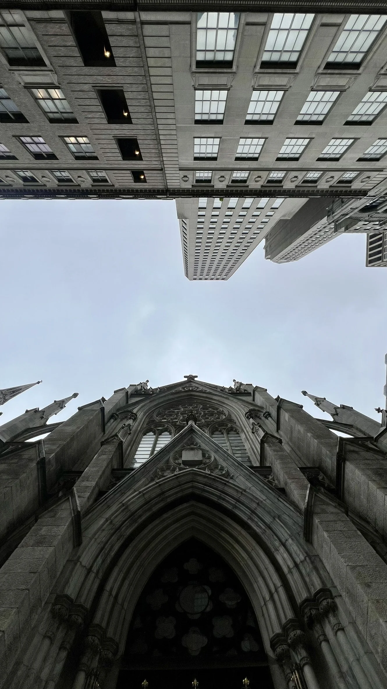 A view looking up at a church and surrounding tall buildings in an urban setting during the daytime.