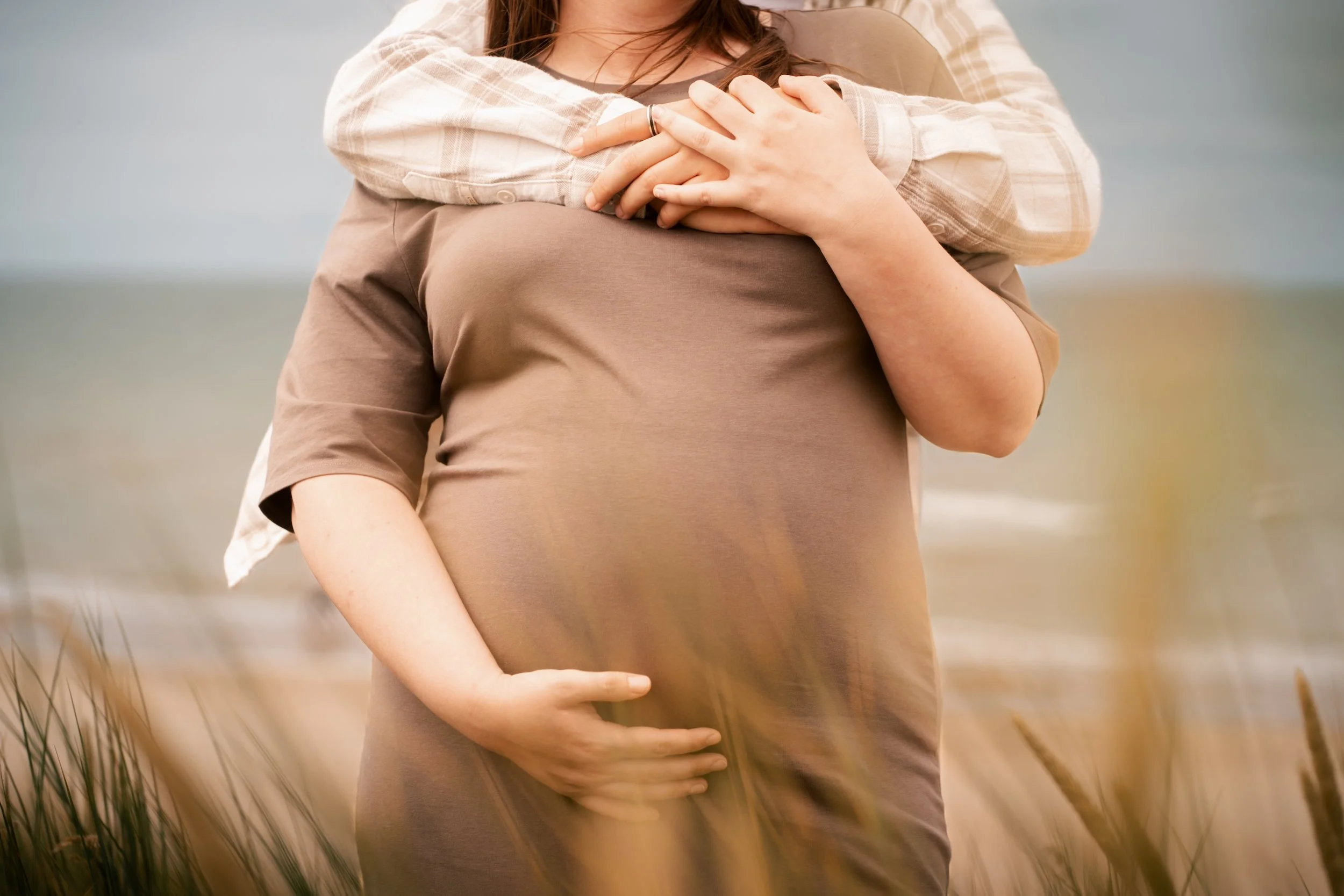 Twee mensen die elkaar omhelzen, één persoon heeft een hand op een zwangere buik.