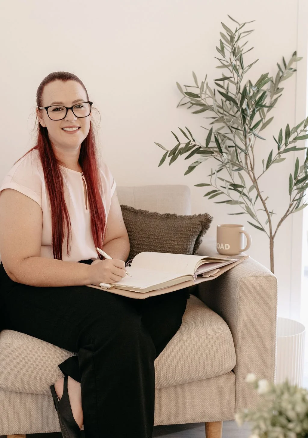 Psychologist Jessica Parker,  psychologist for adolescents and adults on the Gold Coast, is sitting in a warm, welcoming therapy space with natural light and greenery