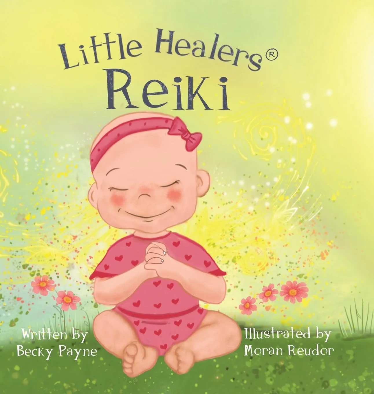 Cover of a children's book titled "Little Healers Reiki" with an illustration of a smiling baby sitting cross-legged with hands clasped, wearing a pink outfit with red hearts and a pink headband, surrounded by flowers and swirls on a green and yellow background.