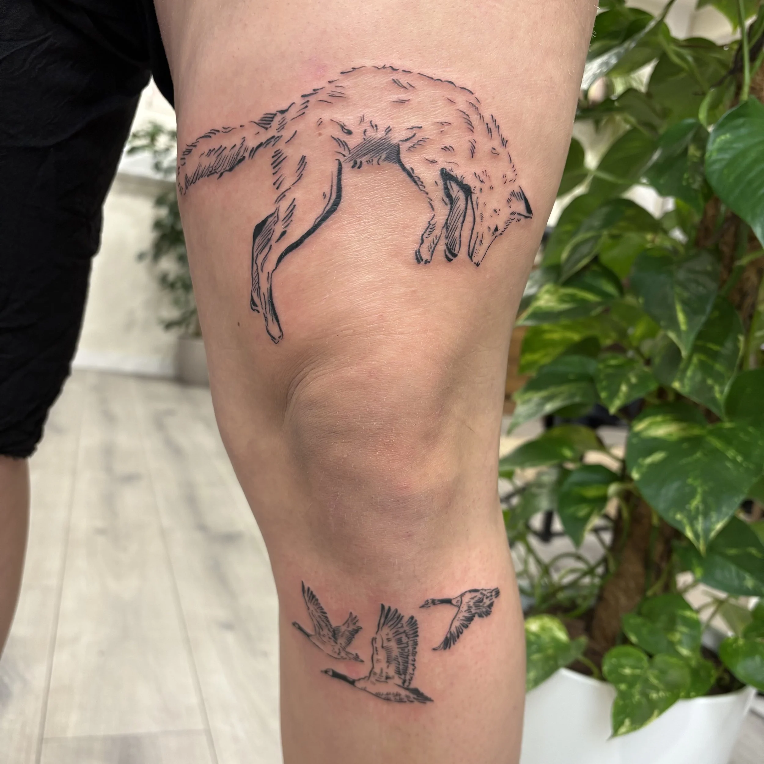 Tattoo of a fox on the upper thigh, and three flying birds on the lower leg.