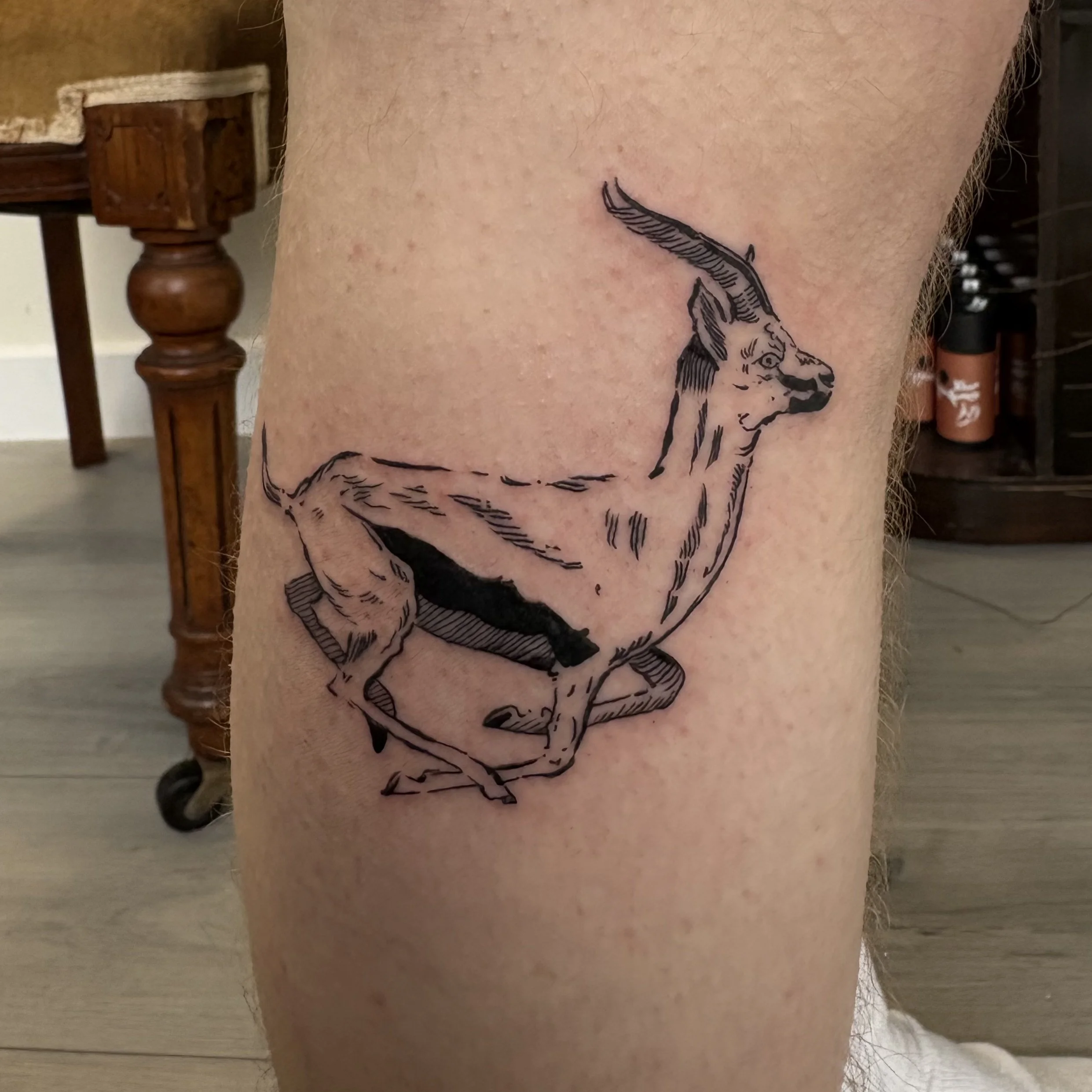 Black and gray line tattoo of a goat with large, curved horns