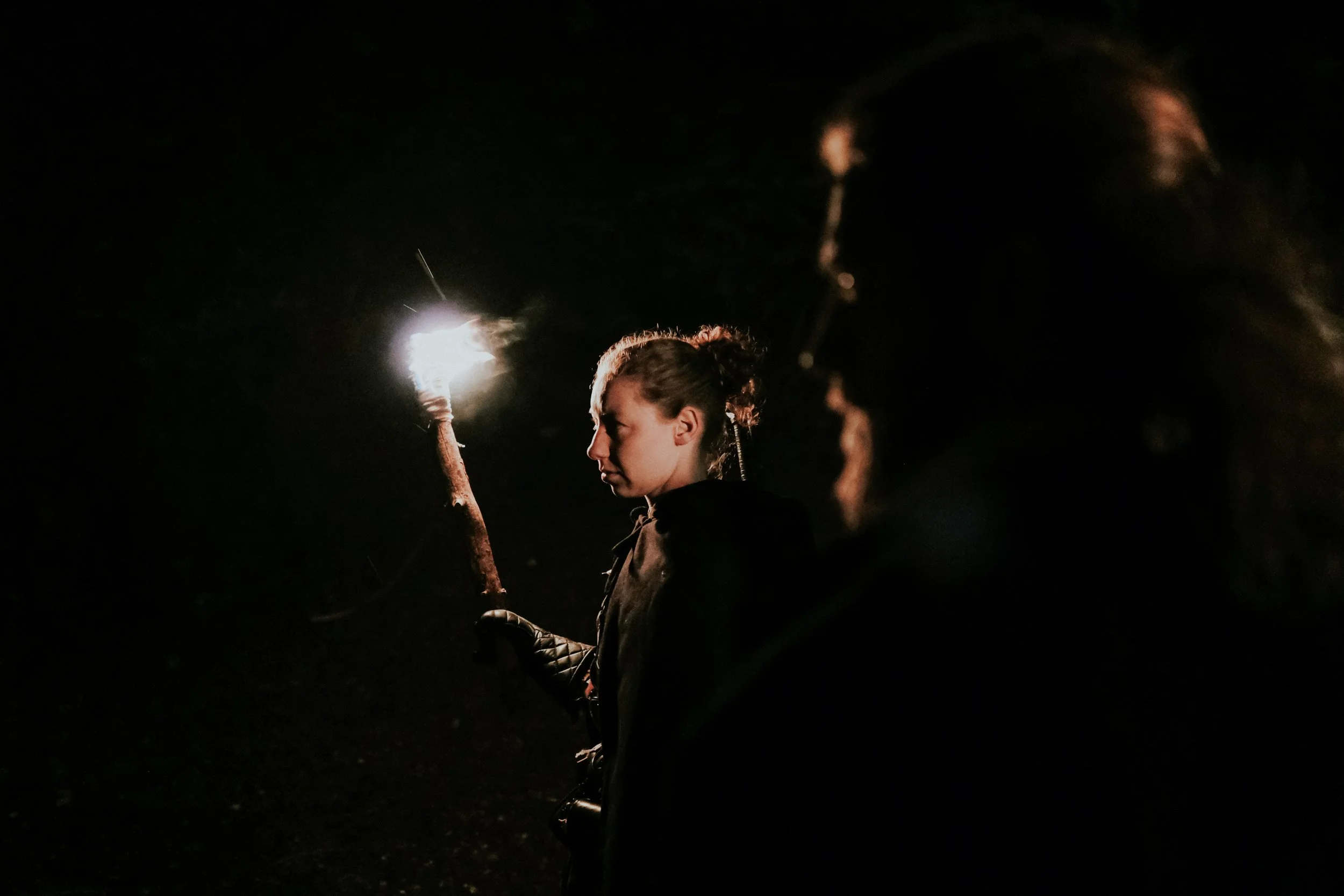 A woman holding a lit sparkler at night, with a dark background and only her silhouette and the sparkler visible.