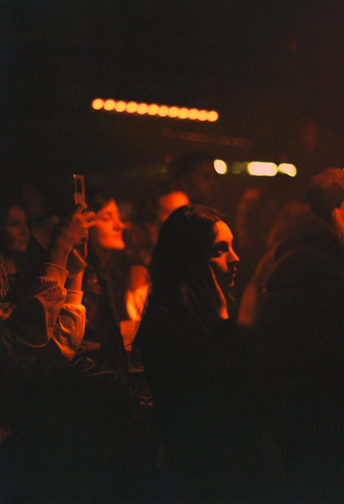 Une foule de personnes assises dans une salle sombre, regardant un spectacle ou une présentation, certaines prenant des photos avec leur téléphone