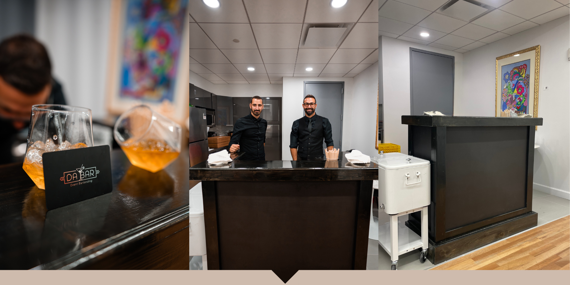 Two men standing behind a bar counter in a modern kitchen, smiling at the camera. The bar has a black countertop with napkins and a few items. To the right, there is a black reception desk with a framed colorful abstract artwork on the wall behind it
