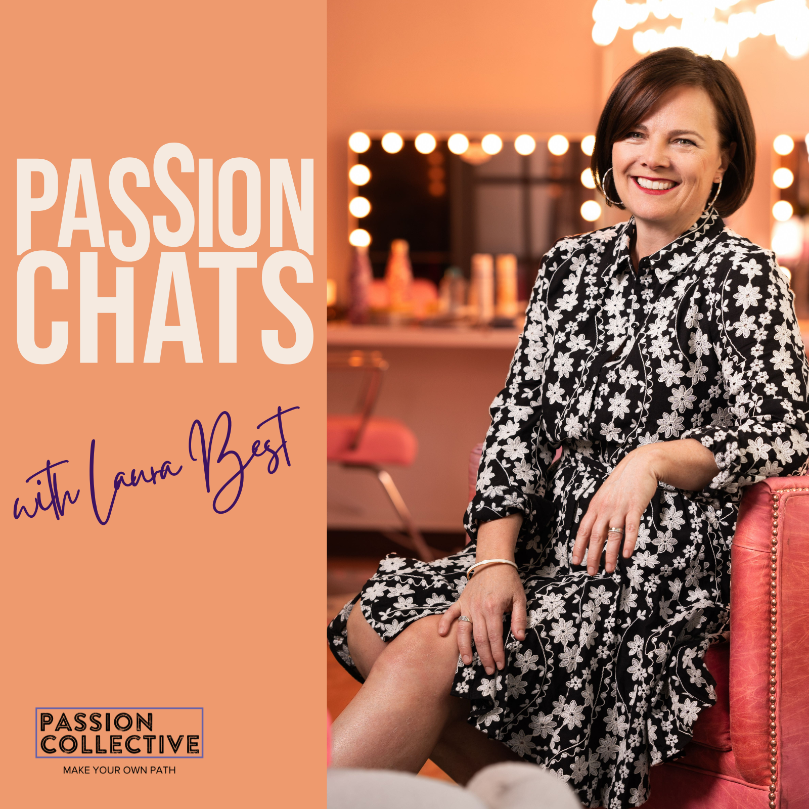 A woman with dark hair smiling, sitting on a pink chair in a warmly lit room decorated with string lights and a mirror, wearing a black and white floral dress.