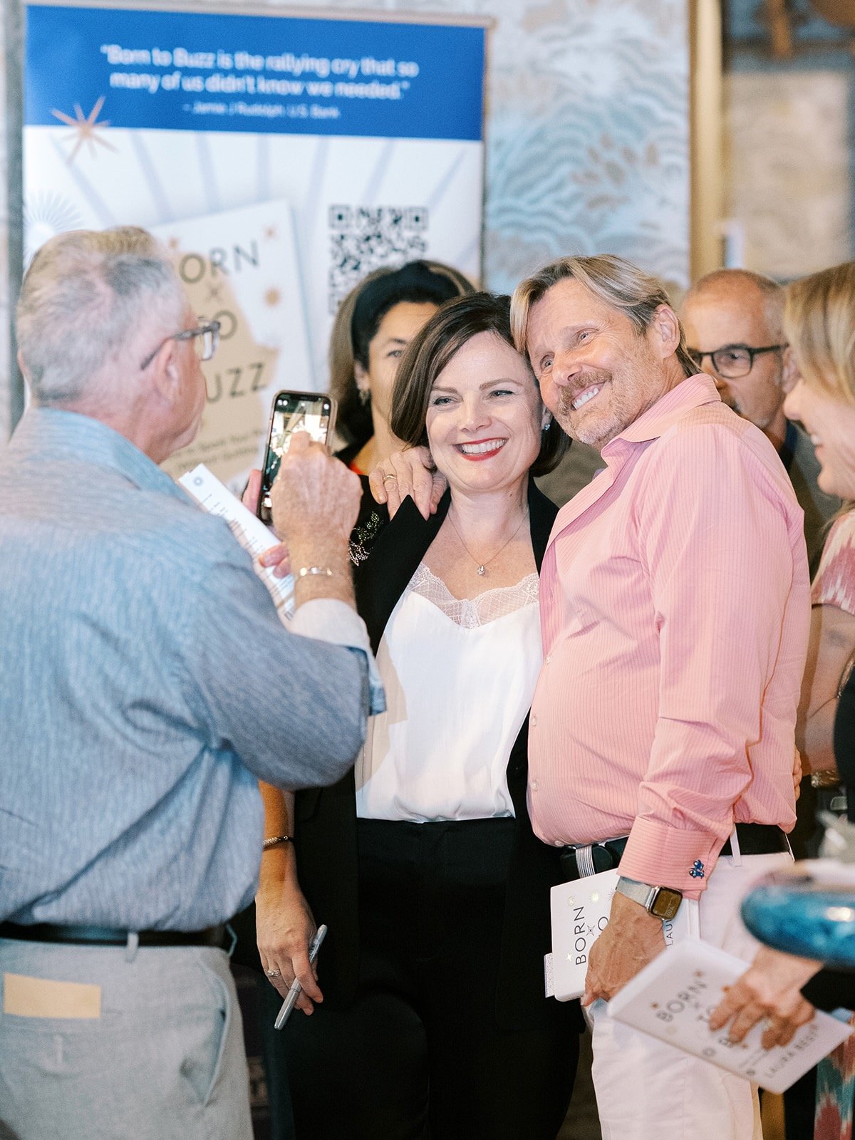 A woman speaking to an audience with a person in a yellow mascot costume, dressed as a lion, at an indoor event or conference.