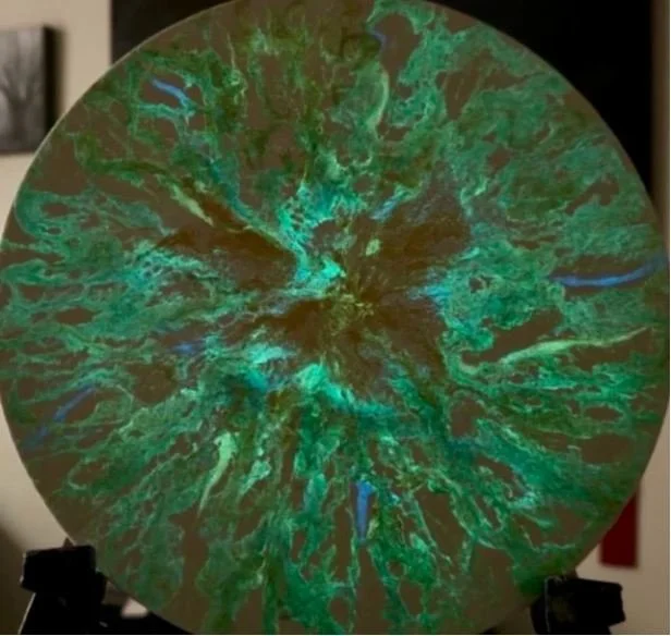 A circular, eco-friendly solar window with colorful, abstract patterns resembling a mineral or geological formation.