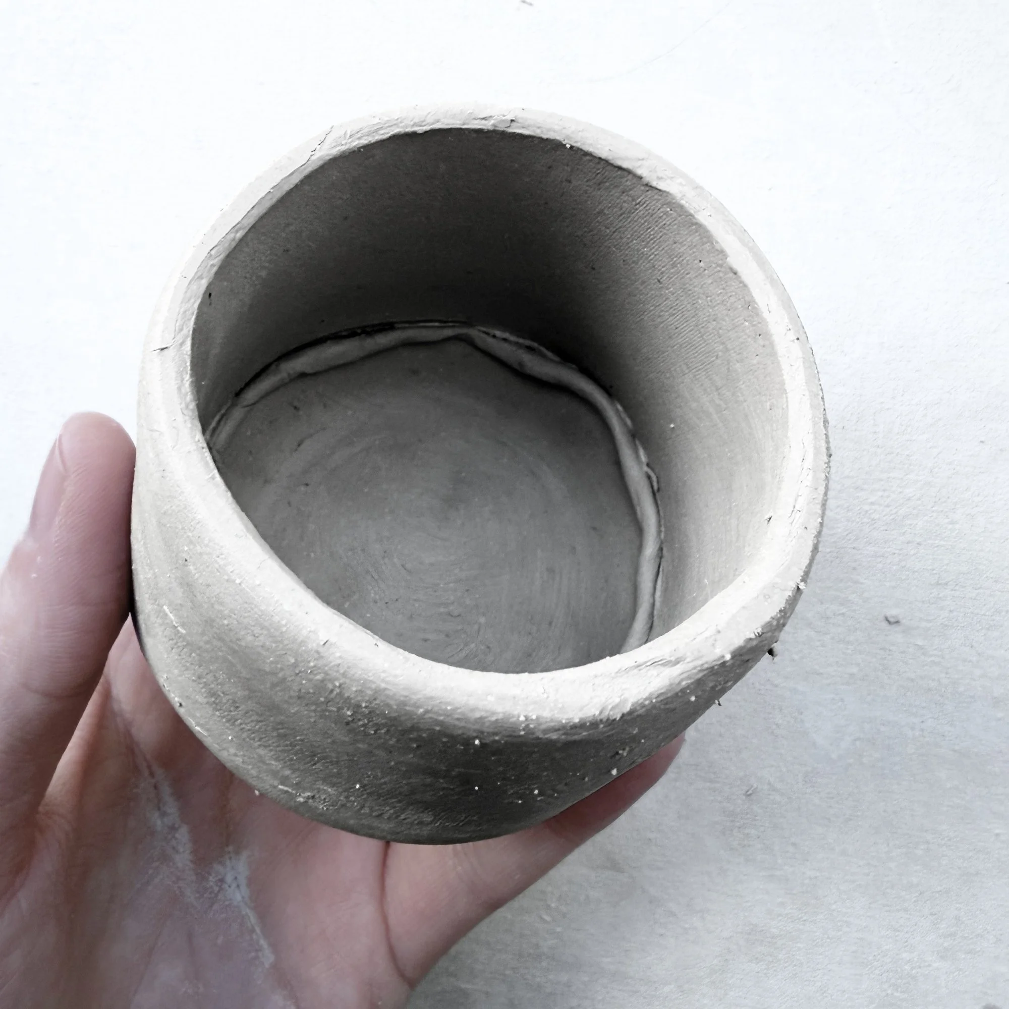 Inside view of handmade round mug, strengthen the seams, slab-built using pottery template, smooth ceramic finish, showing DIY crafting process for beginner potters.